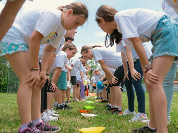 Schoolchildren Standing in Front of a Row of Bowls Lying on Grass