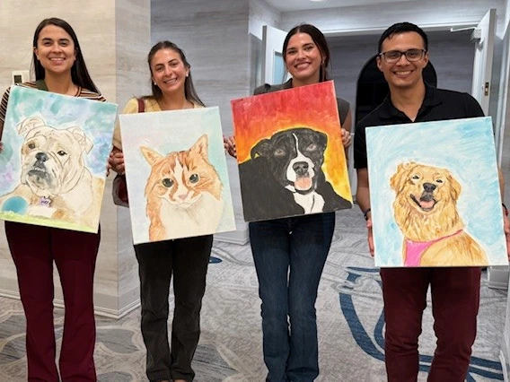 4 people holding up paintings of their pets. 