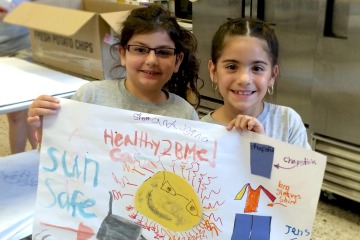 Two young girls holding up a painting