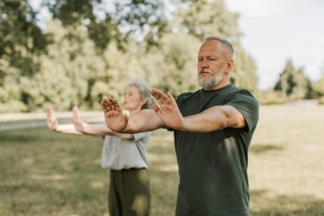 Older man and woman stretching outside.